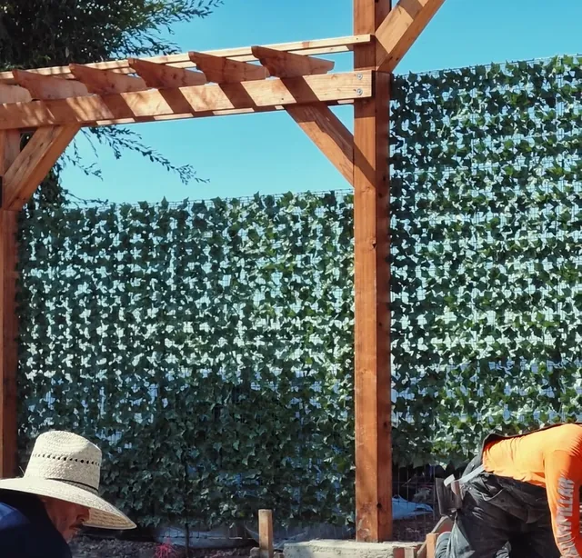 Wood pergola post against a green hedge wall