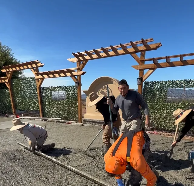 Crew screeding fresh concrete under wood pergolas